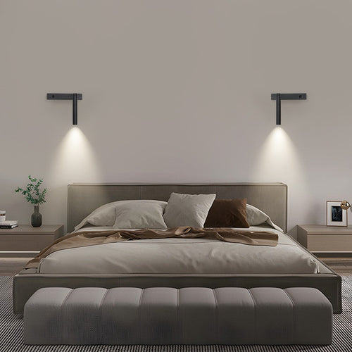 Two black Moodly Beam wall reading lights above a bed, shining down