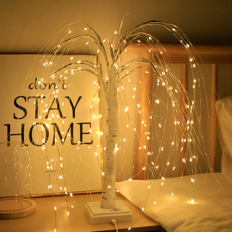White Moodly Willow LED tree lamp glowing on a bedside table