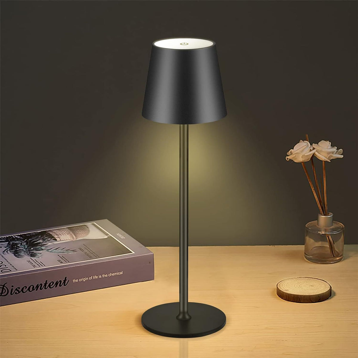Moodly Roam cordless table lamp in black glowing on a wooden table