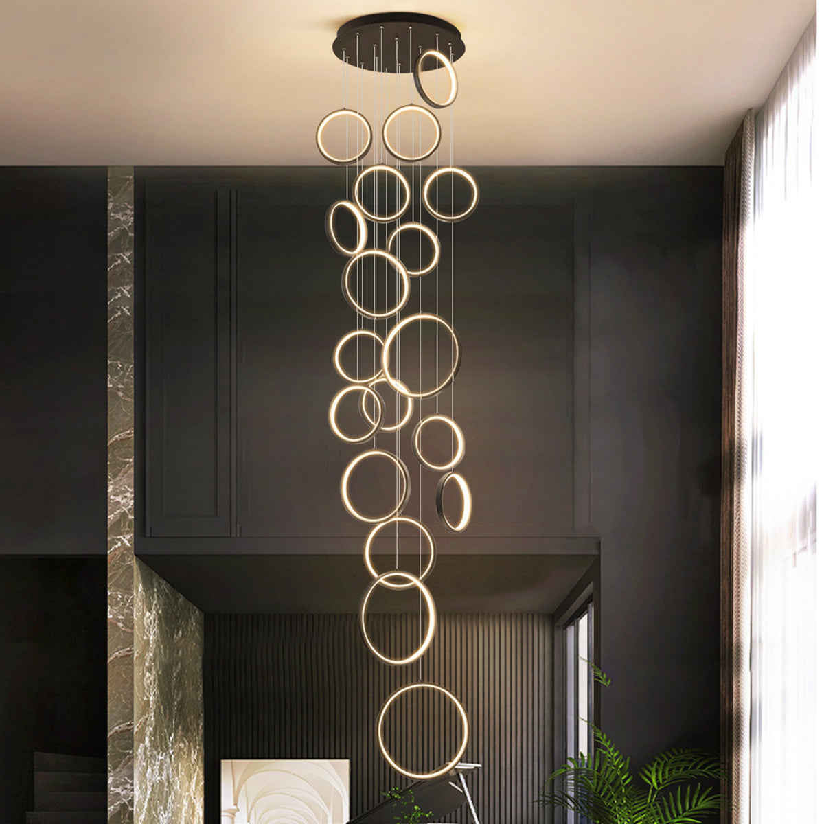 Moodly Orbit LED ring chandelier glowing warm in a dark double-height room